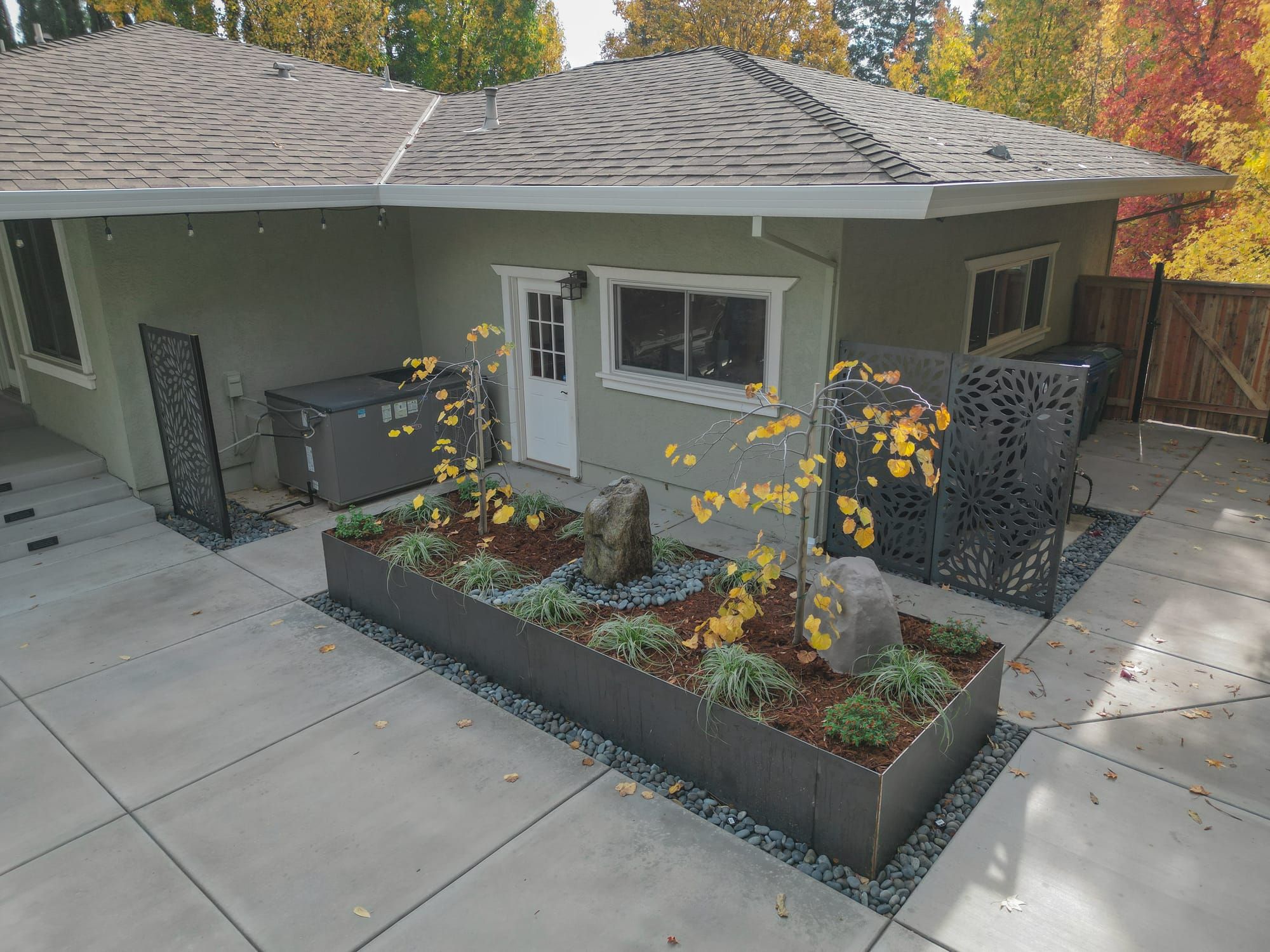 Custom raised planter bed with decorative screens and concrete patio