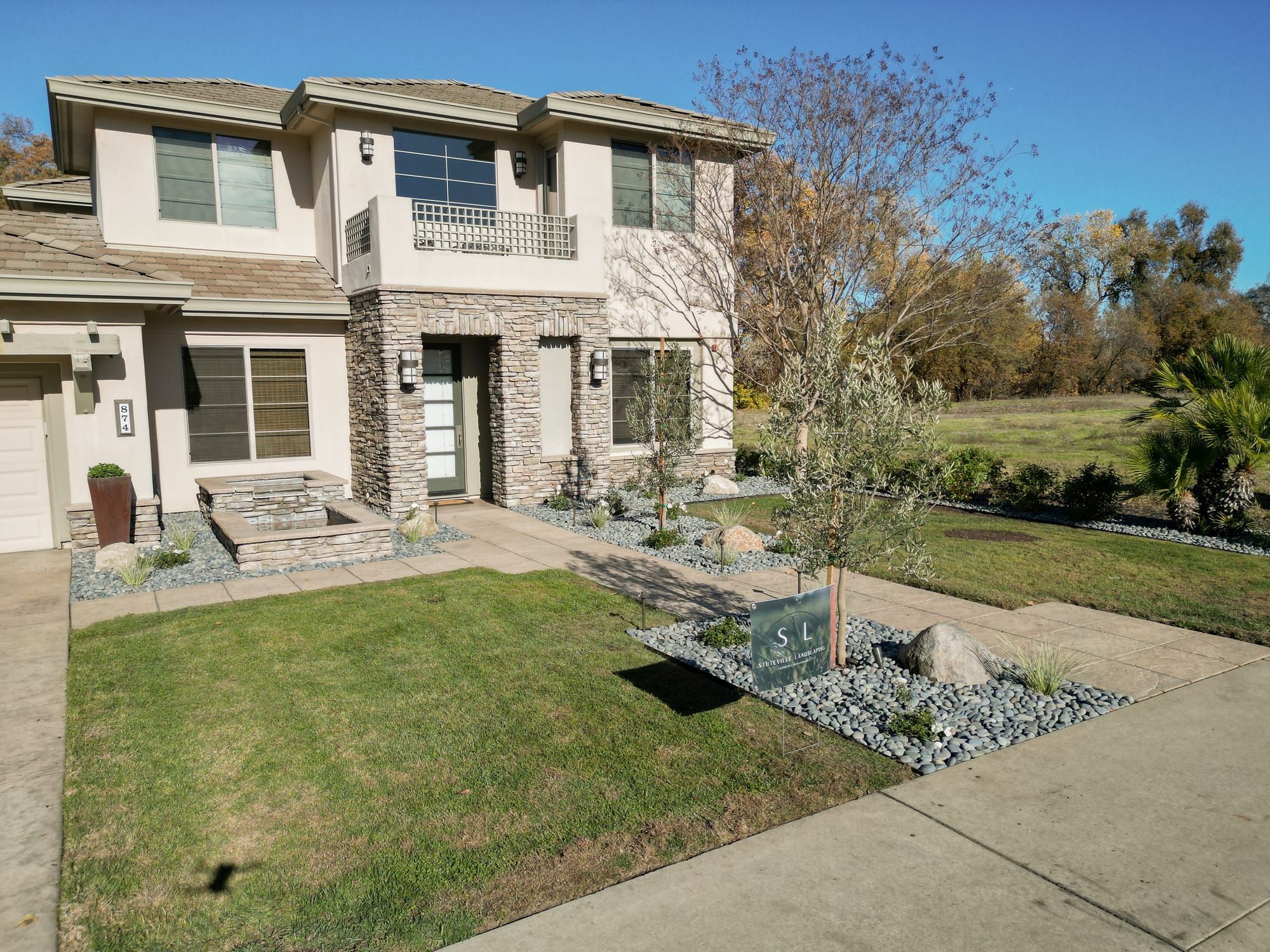 Sacramento front yard landscape design with stone veneer, rock beds, and Stuteville Landscaping sign