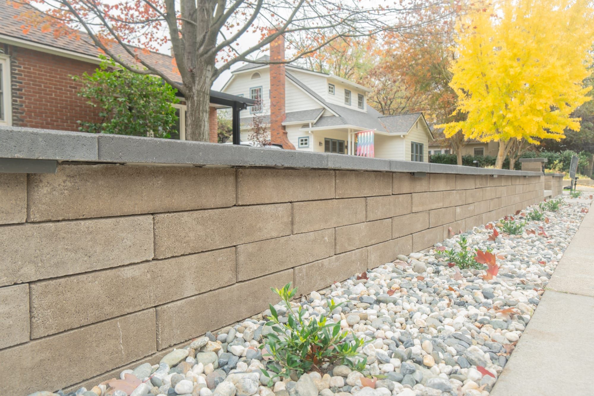 Block retaining wall with cap stones and river rock planting bed along Sacramento sidewalk