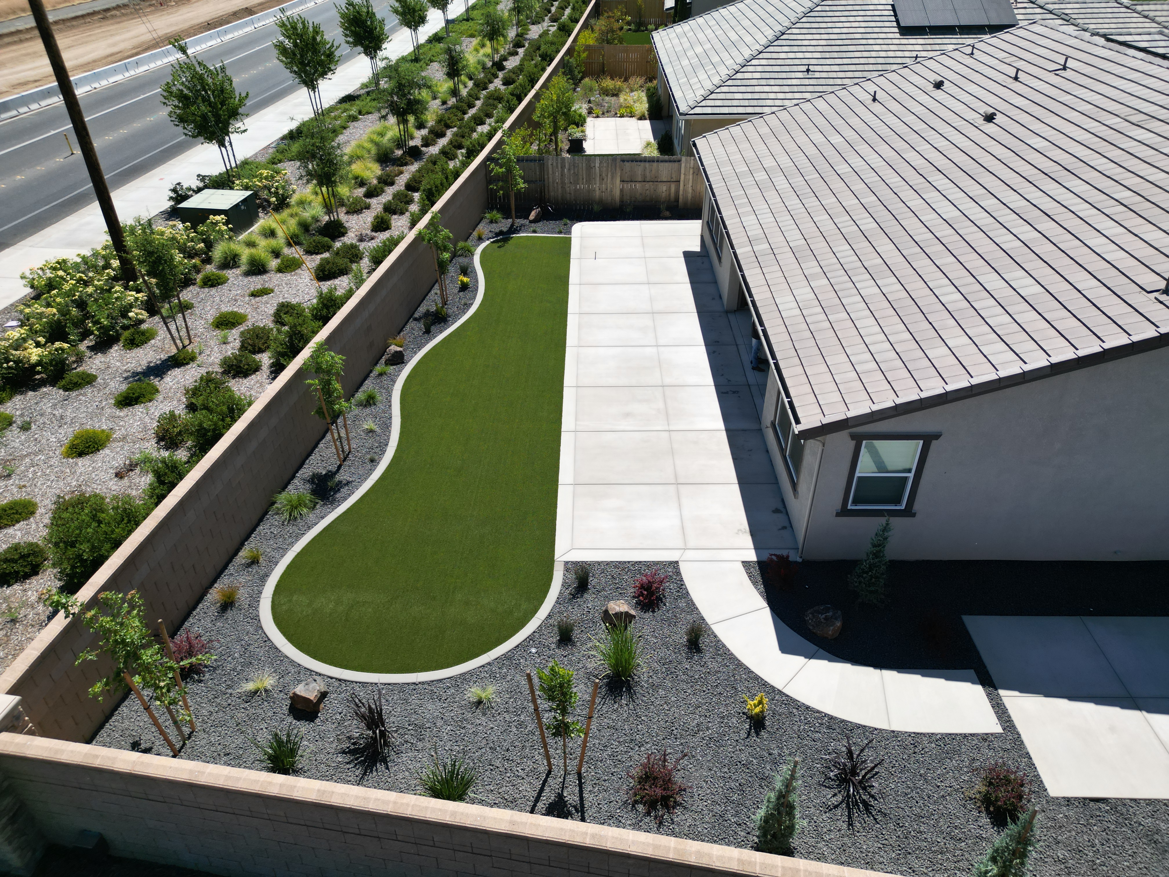 Aerial view of artificial turf installation with decomposed granite, concrete patio, and drought-tolerant plantings in Sacramento