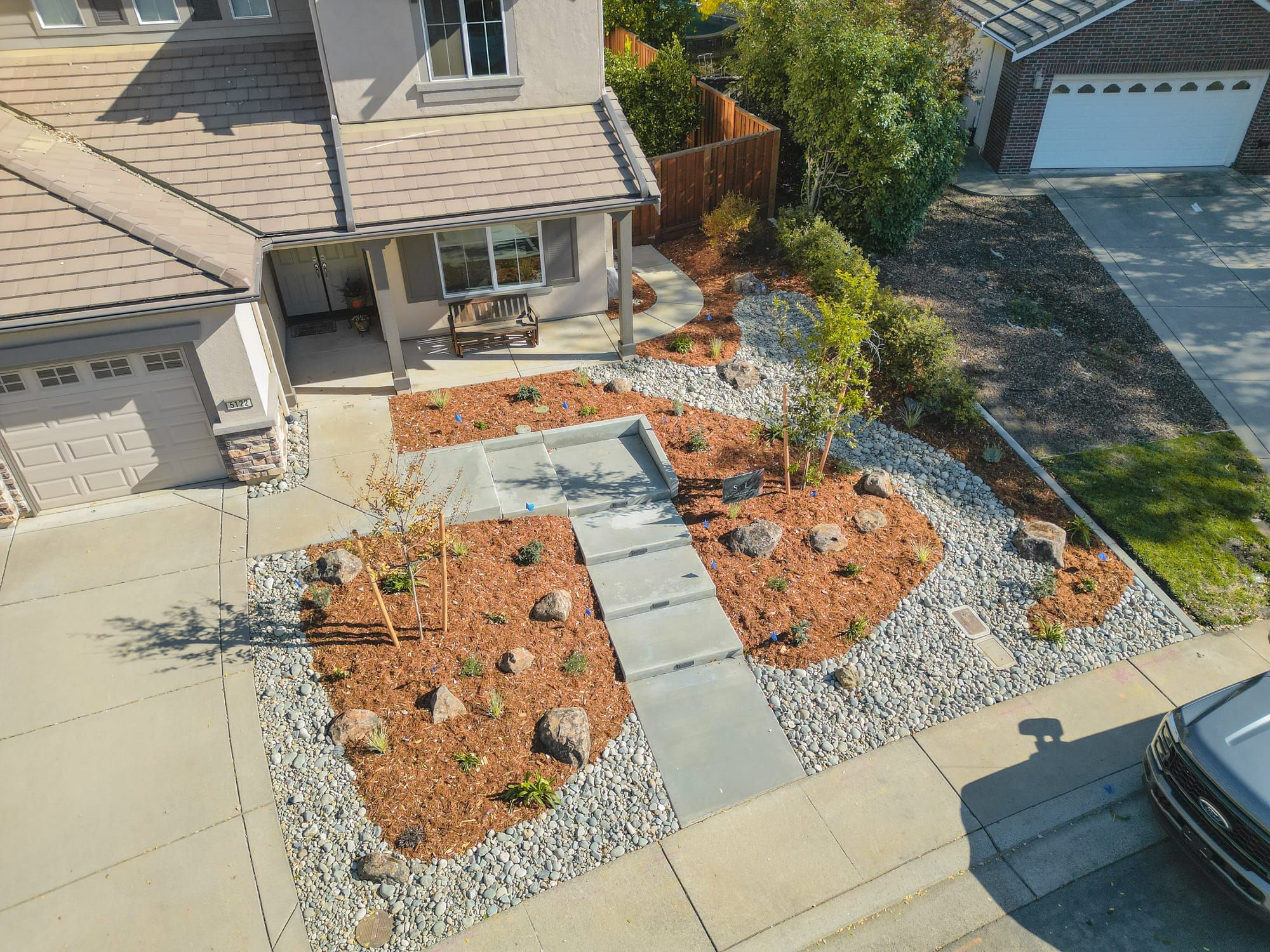 Front yard landscape installation with bark mulch, river rock, drought-tolerant plantings, and concrete steps in Sacramento
