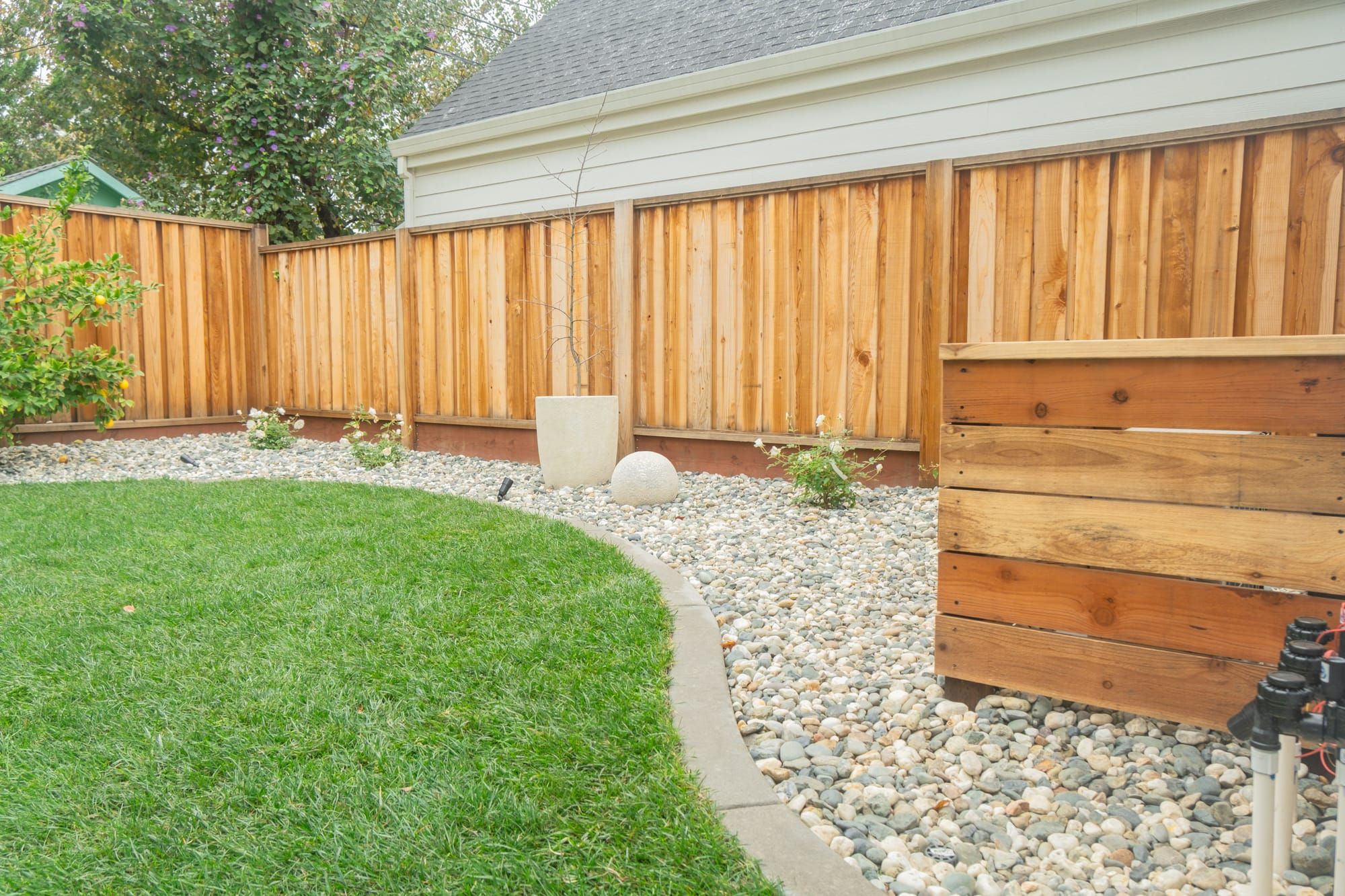 Sod installation with river rock border, irrigation, and cedar fence in Sacramento